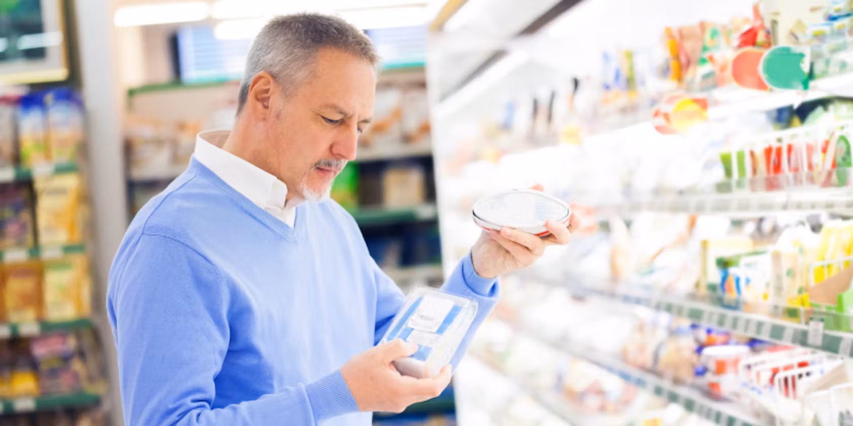 Man in a blue cardigan and white shirt looking at eggs in a market
