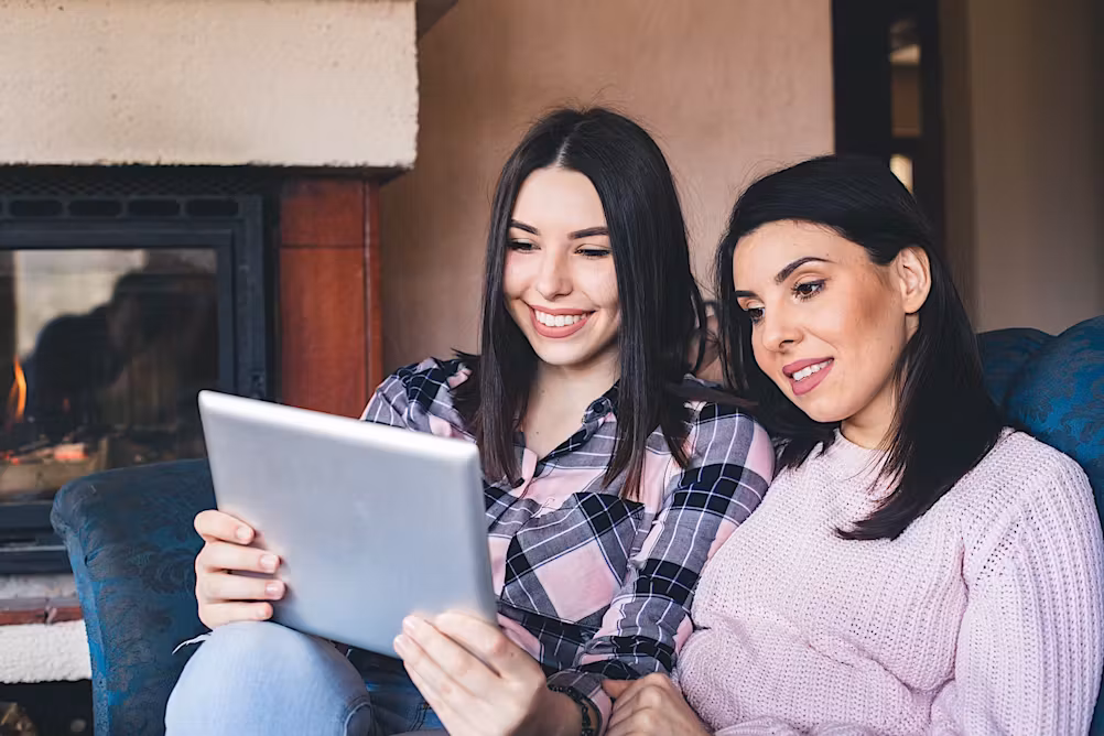 Two women on a couch look at content on a tablet